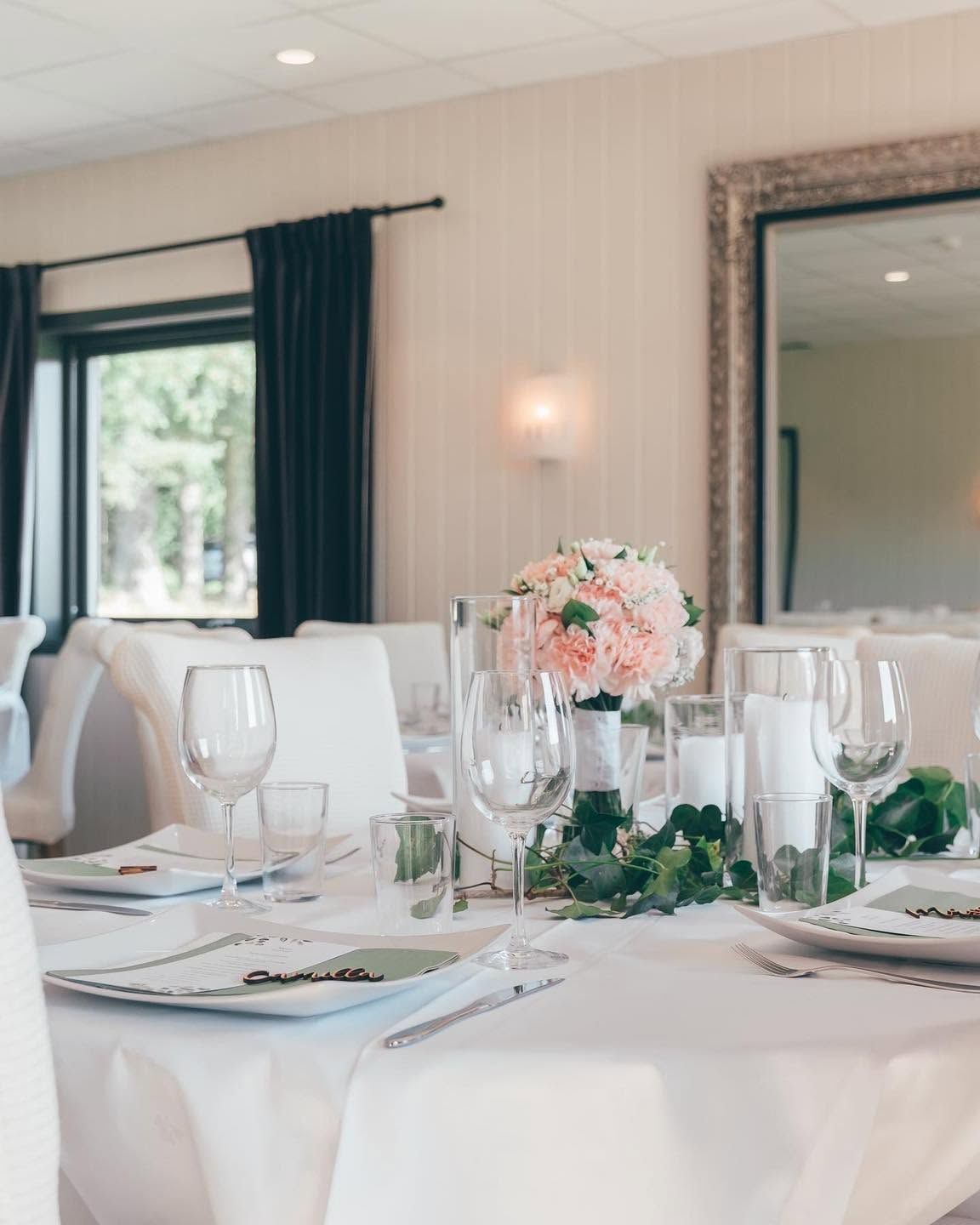 Oppdekket bord med hvit duk, blomsterbukett og glass